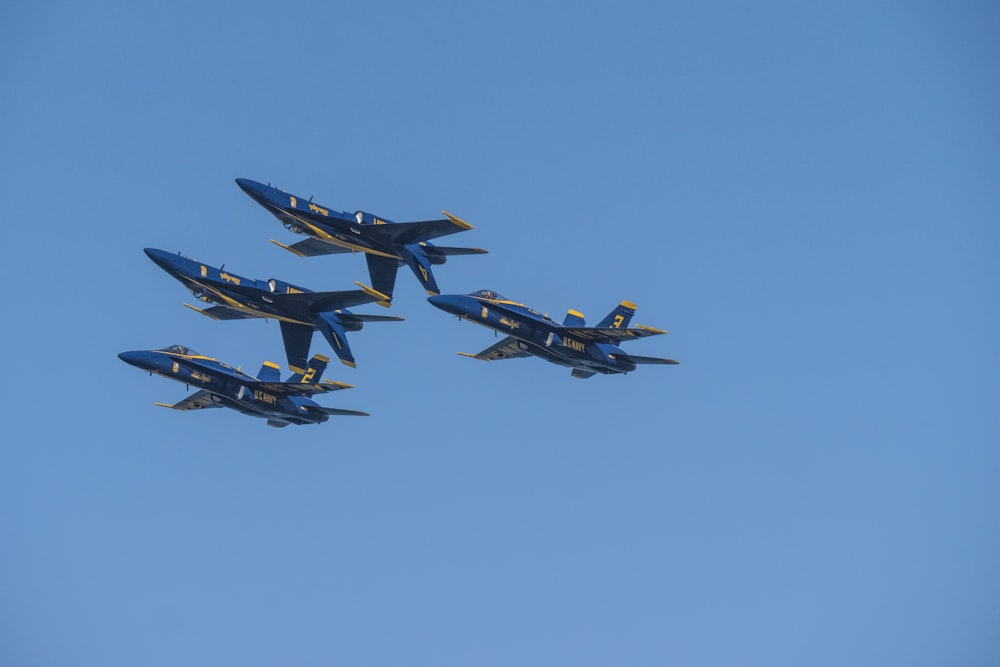 Four blue-and-yellow aircrafts performing an air show trick.
