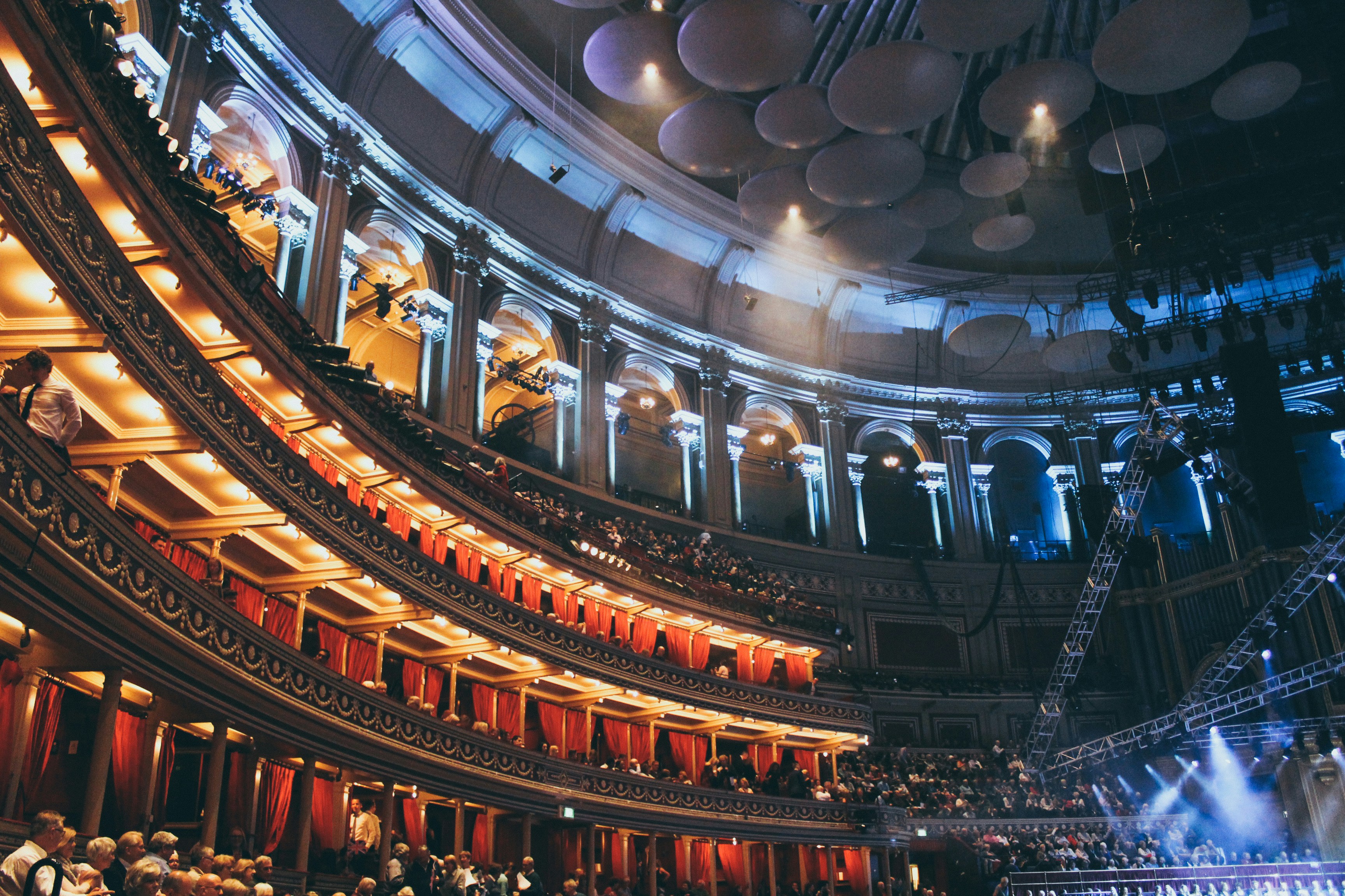 Grand concert hall with dramatic overhead lighting, orchestra setup, powerful and cinematic atmosphere