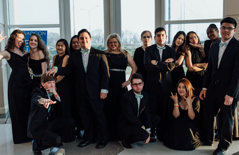 A group of professionals in business attire laughing and posing inside a sleek luxury photo booth at a corporate holiday party.