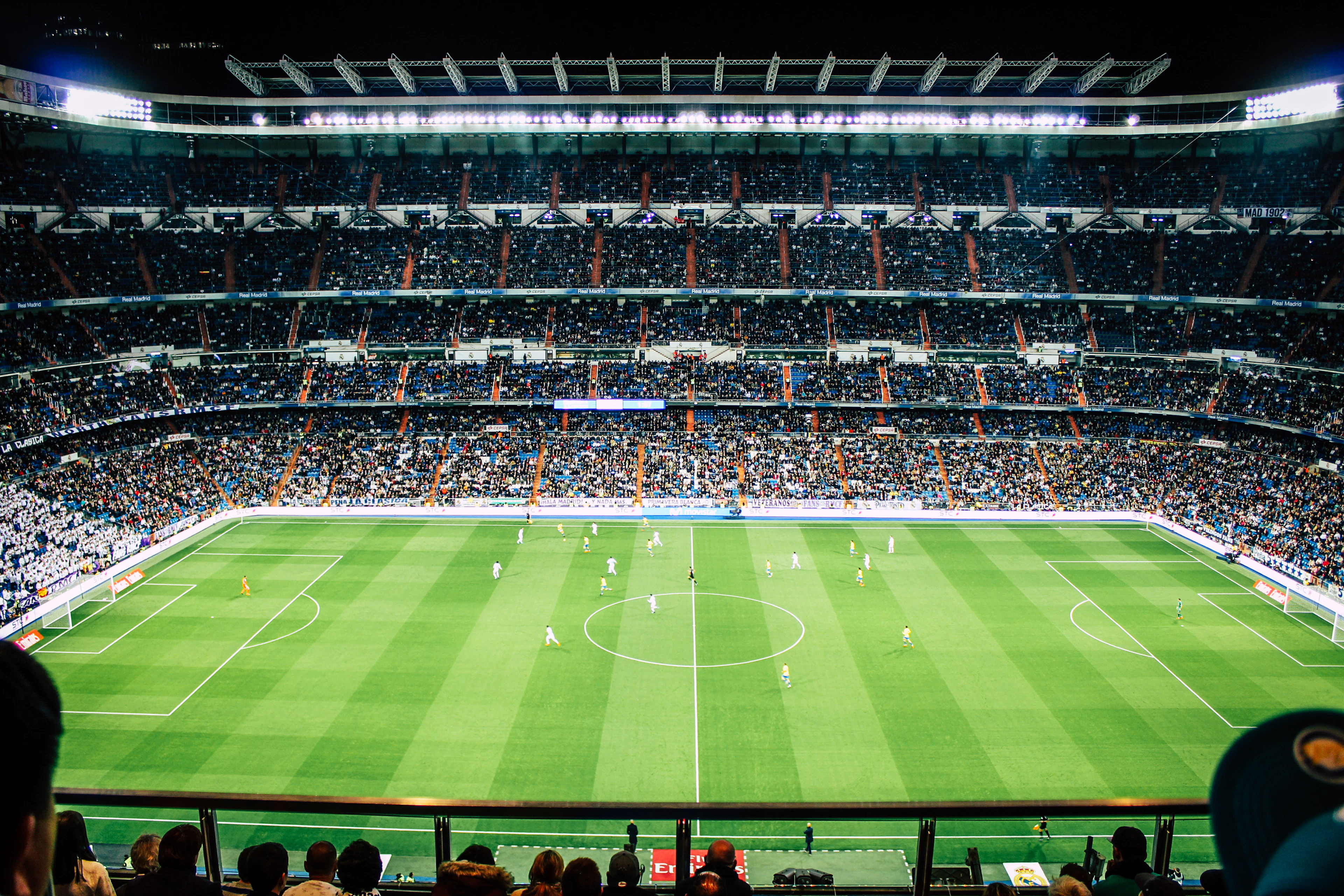 Işıklandırılmış, tribünleri dolu bir futbol stadyumu