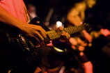 Close-up of a guitarist’s hands strumming with intensity under stage lights.