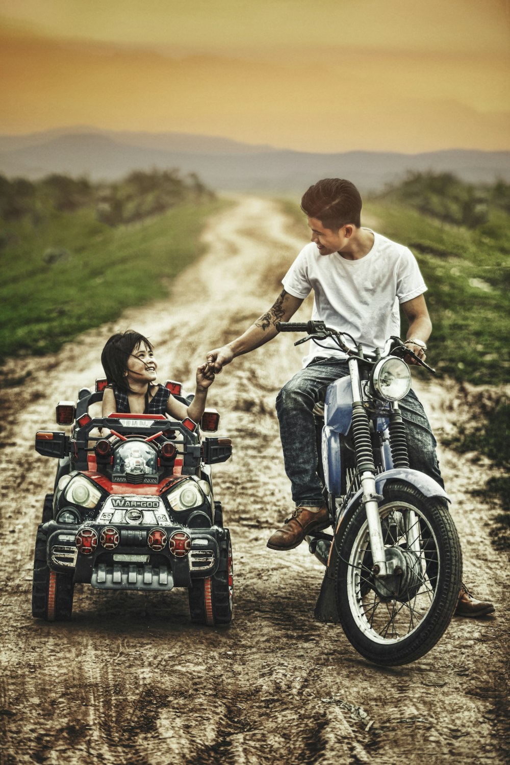 hombre montando motocicleta y niño pequeño en un coche de juguete en una carretera durante el día