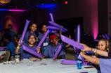 Community members gathered at a Kara Braxton Foundation event, wearing shirts in vivid purple and gray orange.