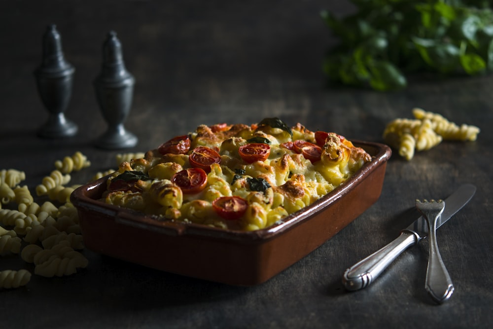 Mac auf brauner Keramikschüssel neben Gabel und Messer backen