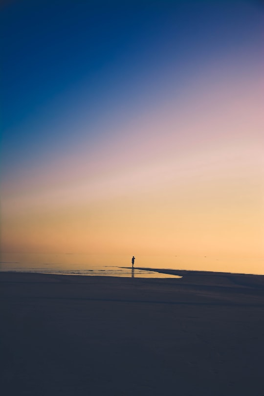 person standing on beach shore during golden time in Huvadhu Atoll Maldives