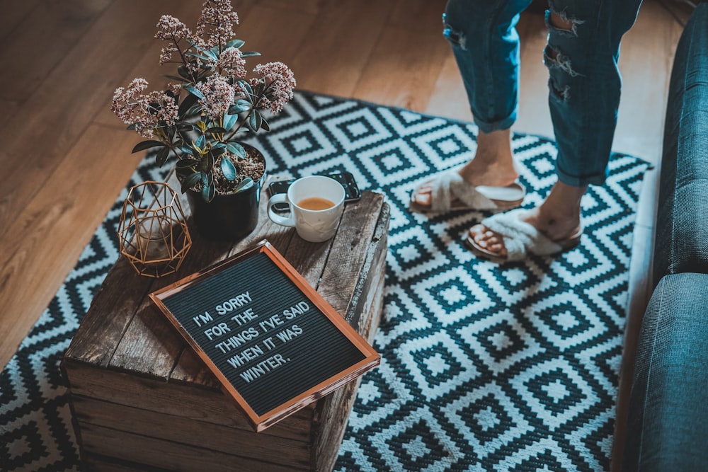 framed sorry quote on table beside half-filled mug