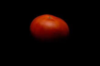 Close-up of a vibrant, ripe crimson tomato on a crisp parchment background.
