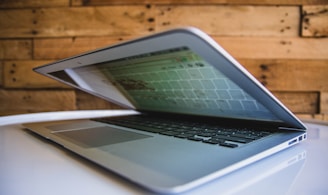 MacBook computer on white surface near brown wall