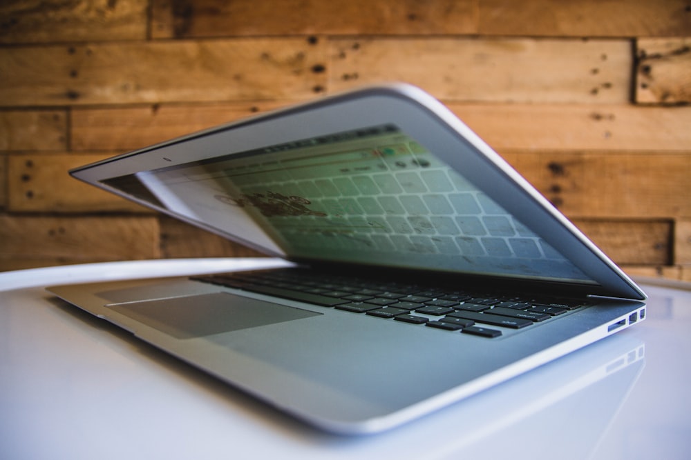 MacBook-Computer auf weißer Oberfläche in der Nähe von brauner Wand