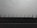 A road with a concrete barrier featuring upright posts, set against a hazy and overcast sky.