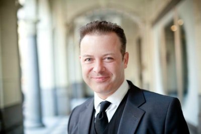 A candid shot of a man in a tailored suit from Lumina Apparel, laughing under warm city lights.