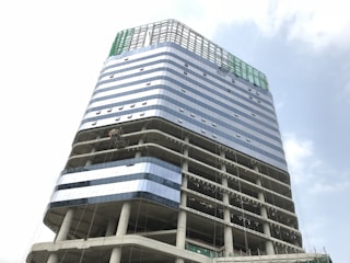 Modern commercial building under construction with glass facades reflecting the sky.