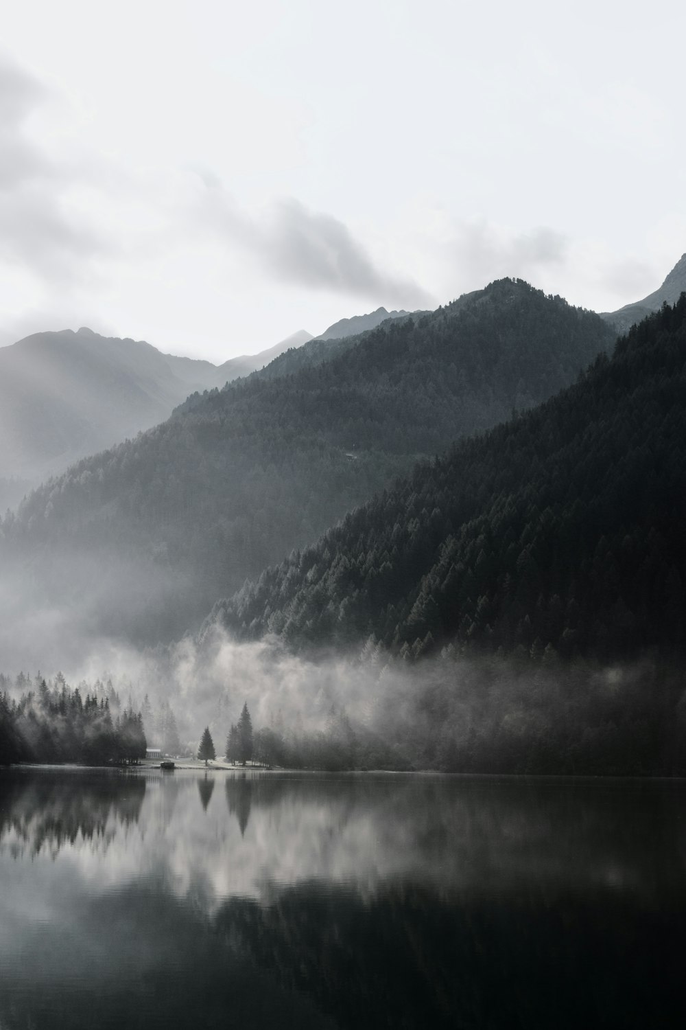 grayscale photography of mountain range with body of water