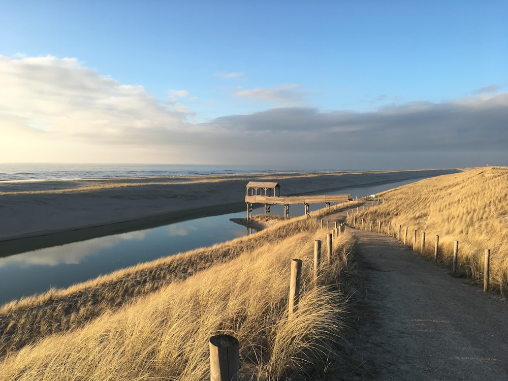 brauner Holzsteg in der Nähe des Sees unter blauem Himmel