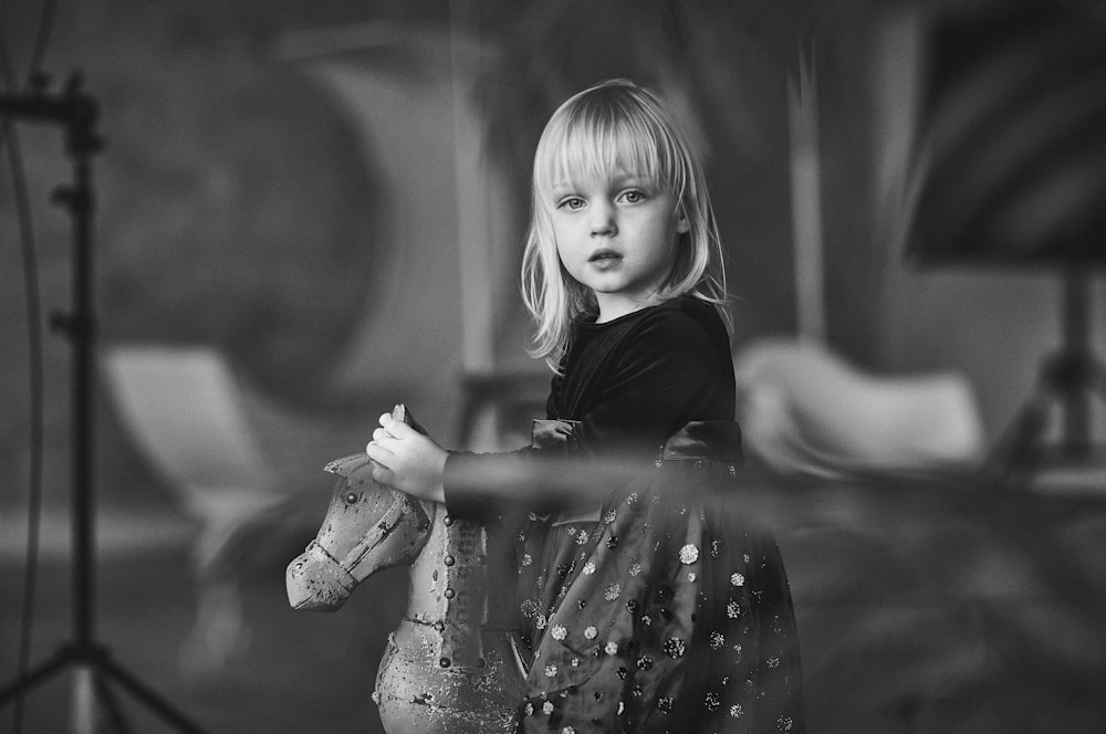 grayscale photo of girl riding horse toy