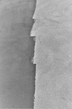 a black and white photo of a wave in the sand
