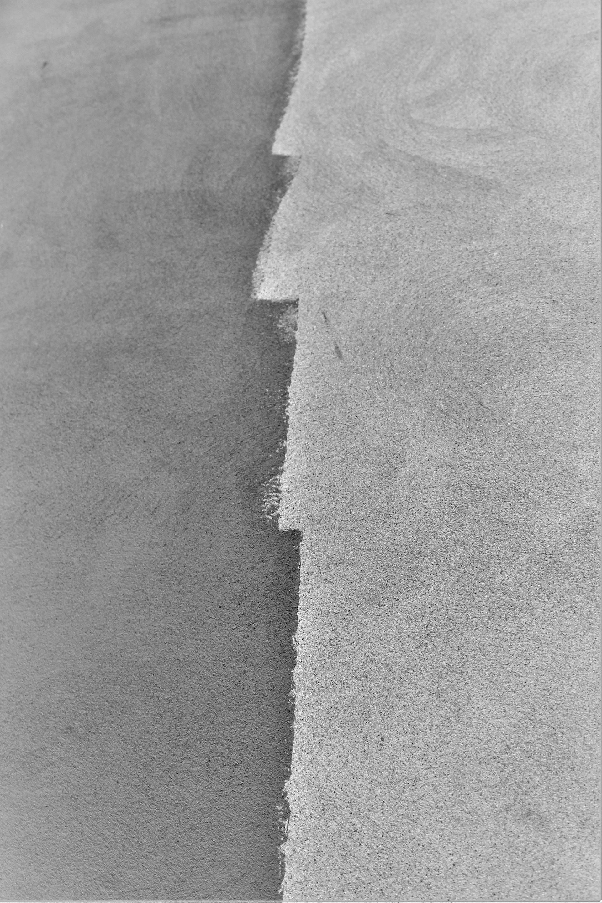 a black and white photo of a wave in the sand