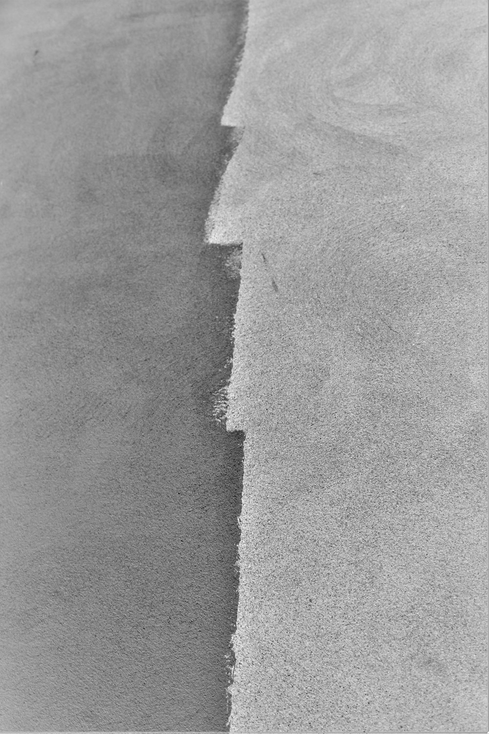 Una foto en blanco y negro de una ola en la arena
