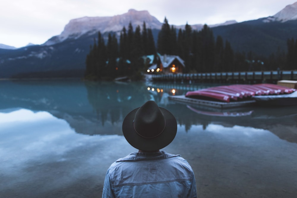 Mann, der vor dem Wasser mit Booten am Dock steht, mit Haus in der Nähe