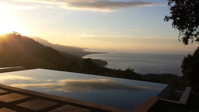 Wide-angle shot of a serene infinity pool blending into a twilight ocean view.