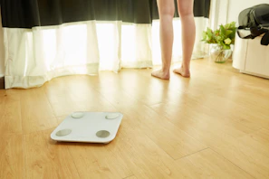 Wies standing barefoot on a sunlit wooden floor, stretching with a calm, focused expression.