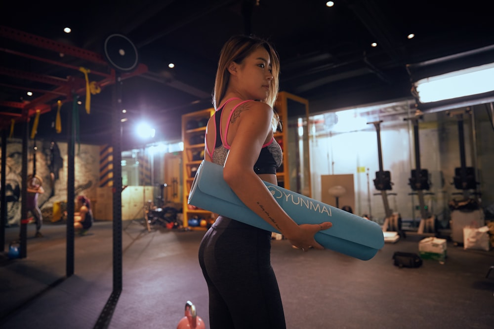 woman holding blue exercise mat