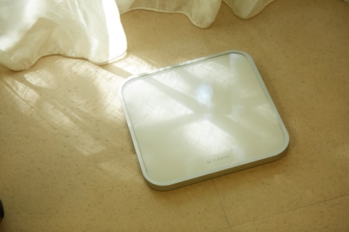 A modern digital scale with a bright display, placed on a clean bathroom floor.