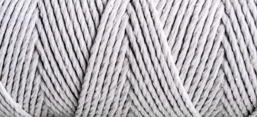 Close-up view of tightly wound, light gray yarn with visible texture and patterns formed by the twisted strands.