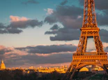 The Eiffel Tower in Paris glowing warmly at sunset with people enjoying the view nearby
