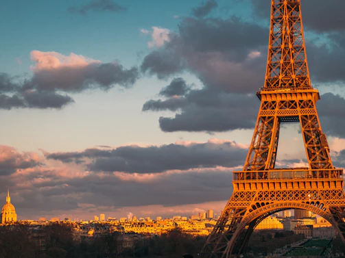The iconic Eiffel Tower glowing at sunset with Paris cityscape in the background.