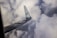 A view of an airplane wing with a logo against a backdrop of dense, fluffy clouds.