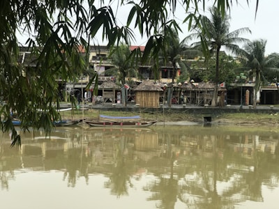 Traditional Vietnamese sampan navigating peaceful river waters with green rice paddies on both sides.