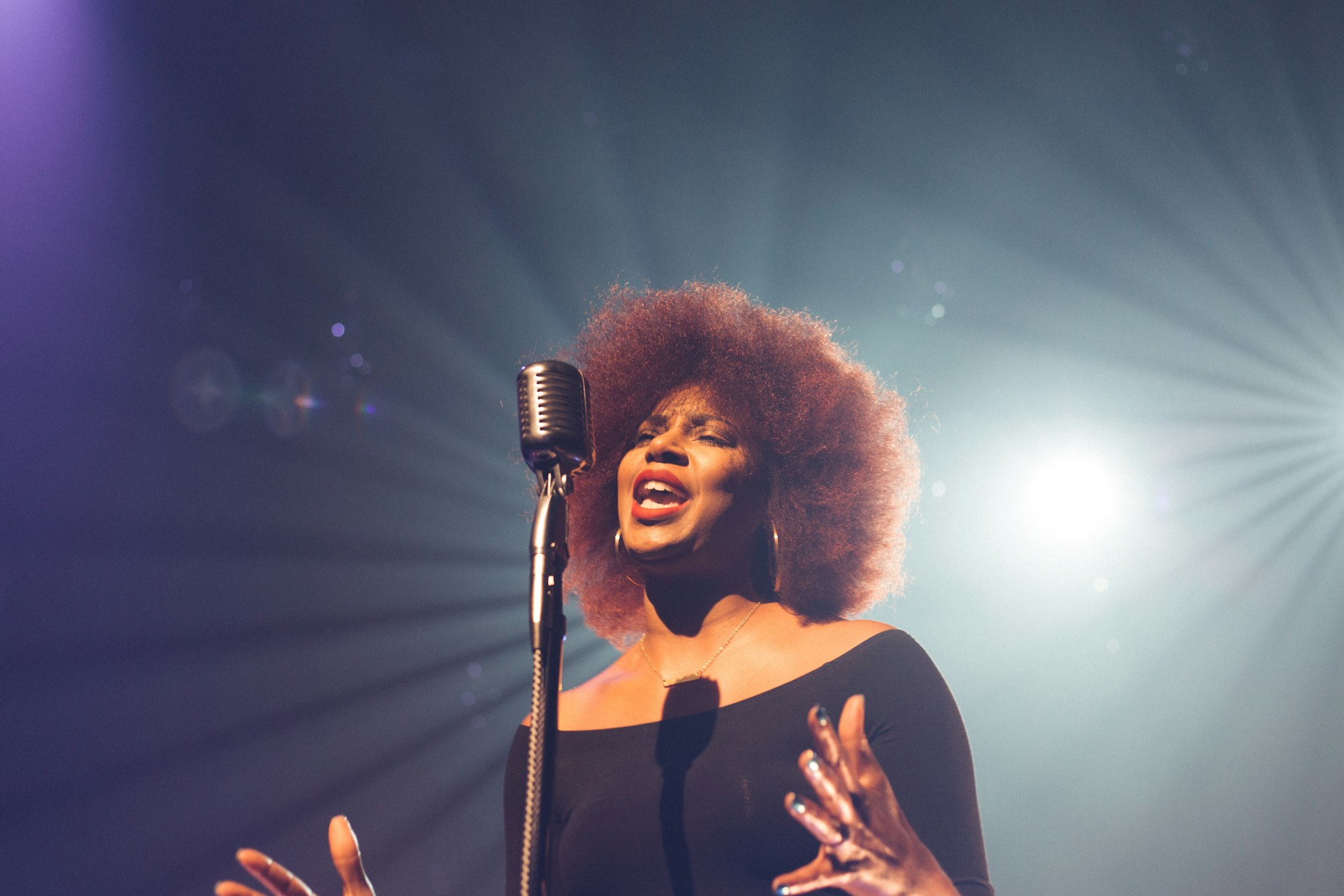 Lady singing into microphone on stage