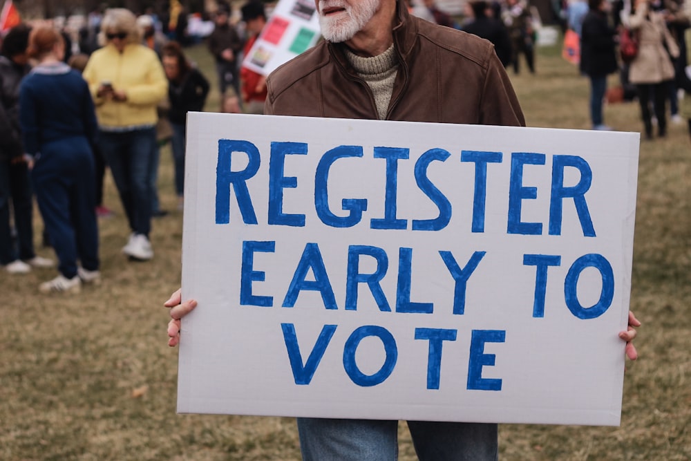 person holding a register early to vote sign