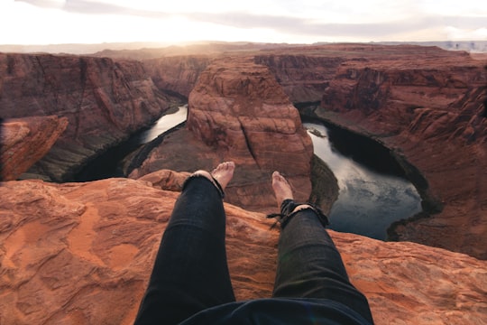person sitting on brown mountain cliff in Lake Powell United States