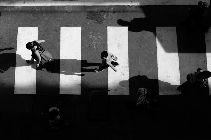 Aerial grayscale shot of pedestrians crossing a street