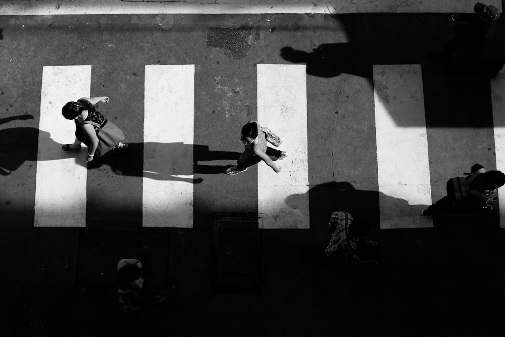 grayscale photo of people crossing pedestrian street