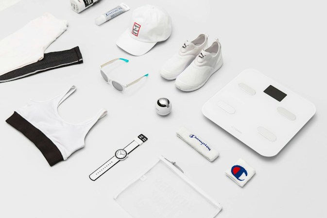 Flat lay of sneakers, sunglasses, a cap, leggings, and a sports bra
