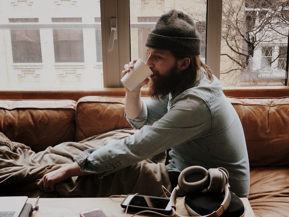 man sitting on sofa while drinking