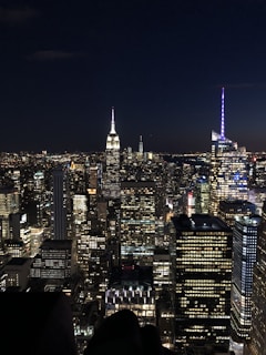 A vibrant cityscape at night showcasing iconic landmarks lit up against the dark sky.