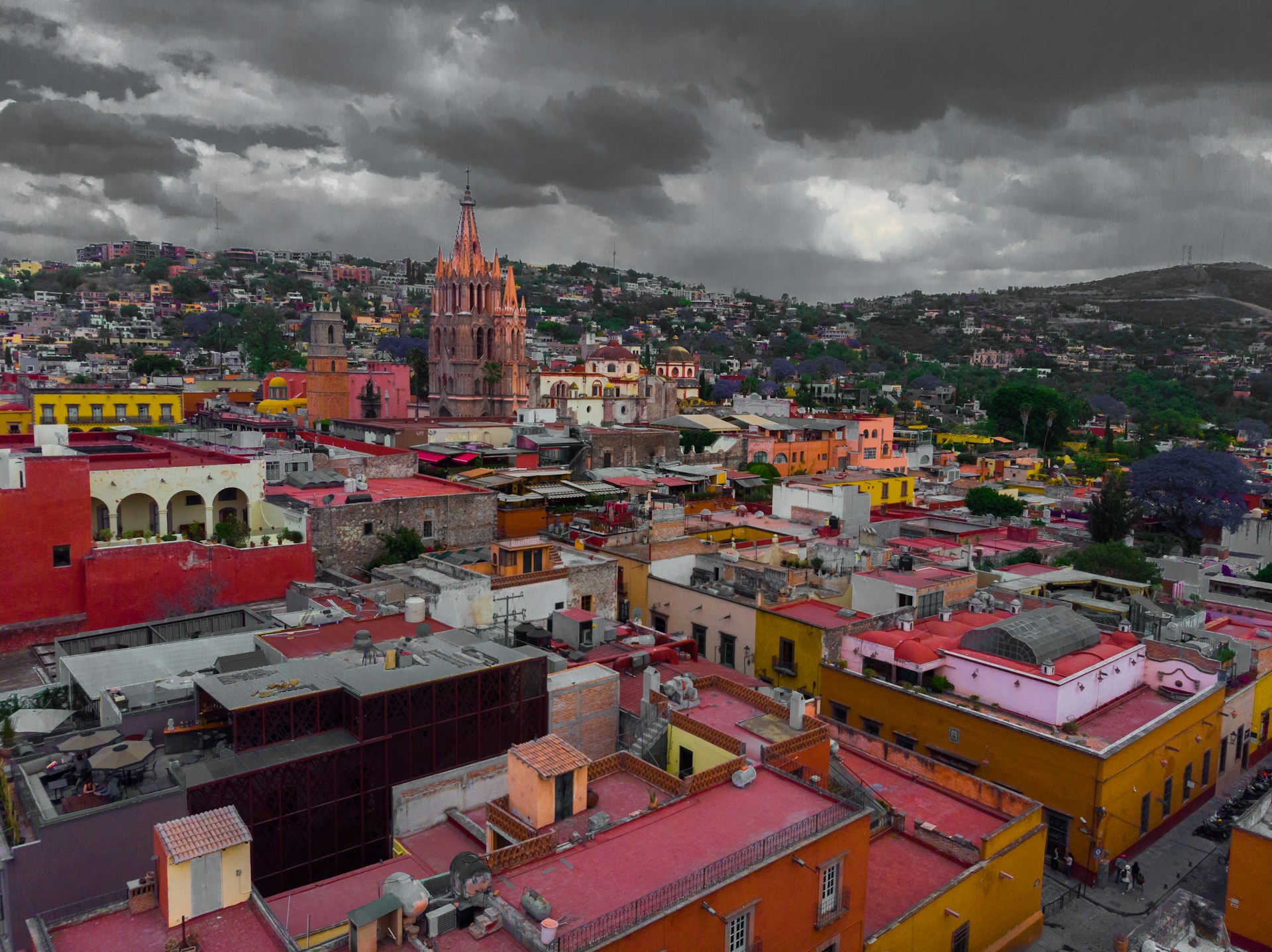An aerial view of San Miguel de Allende at dusk with red and yellow alert icons marking areas of reported incidents.