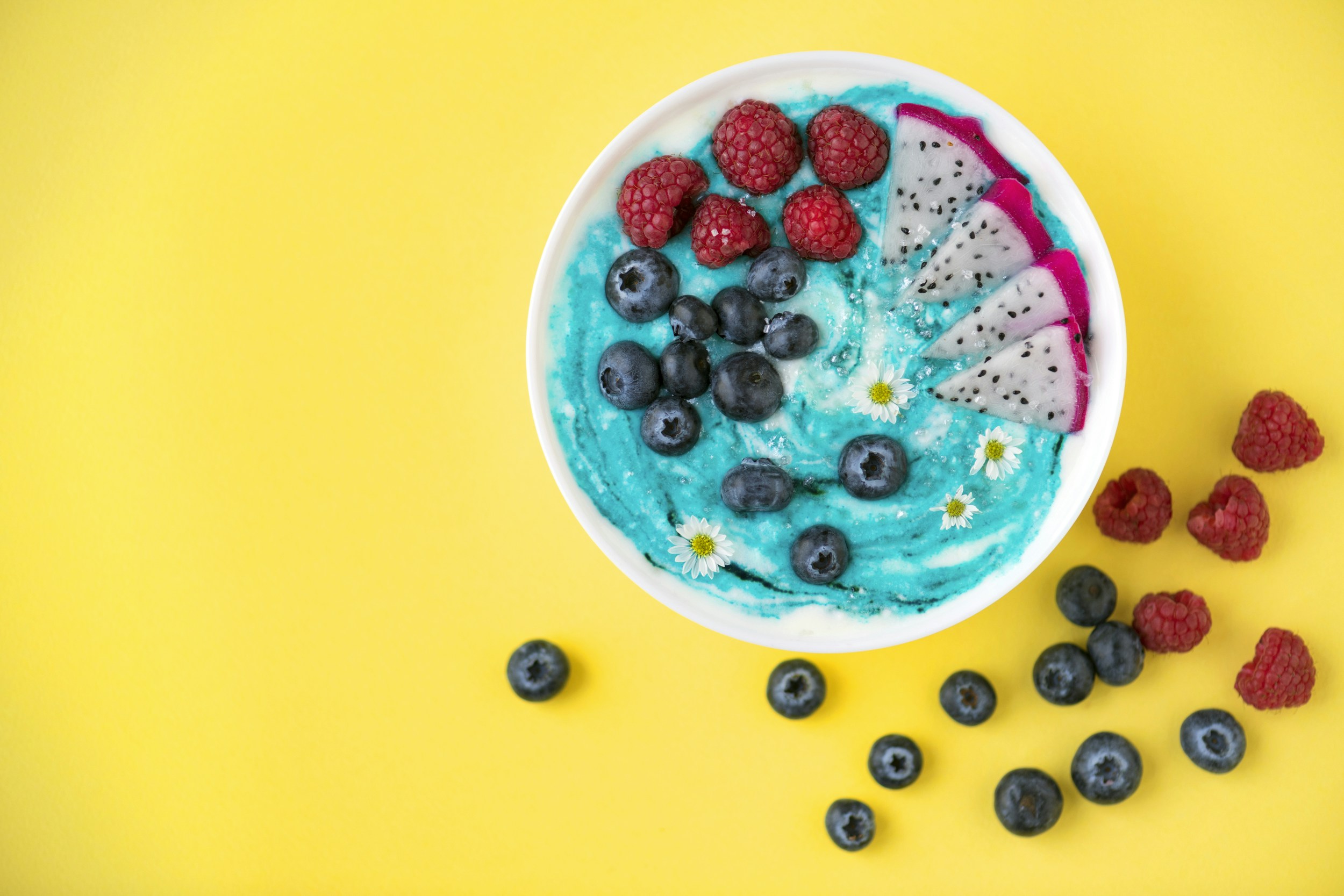 raspberries and blueberries beside white bowl