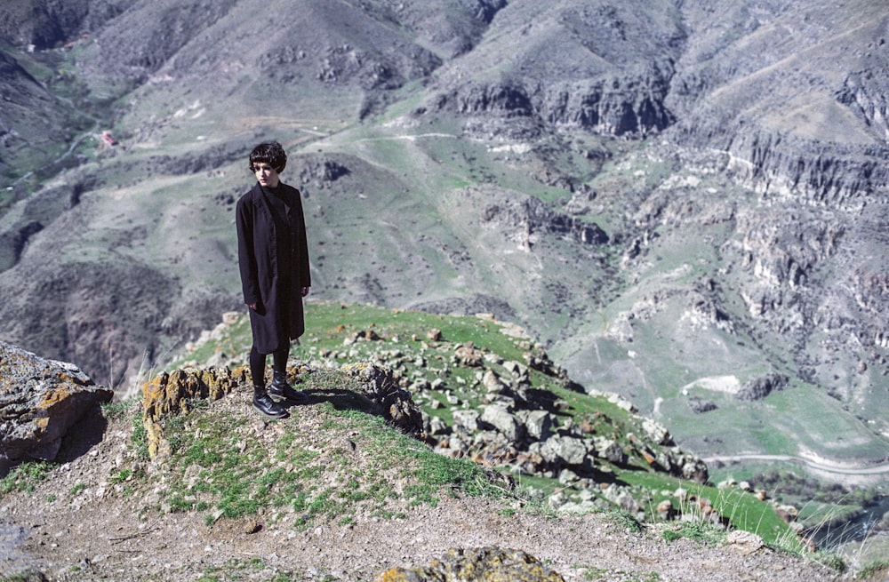 woman standing on cliff wearing black suit