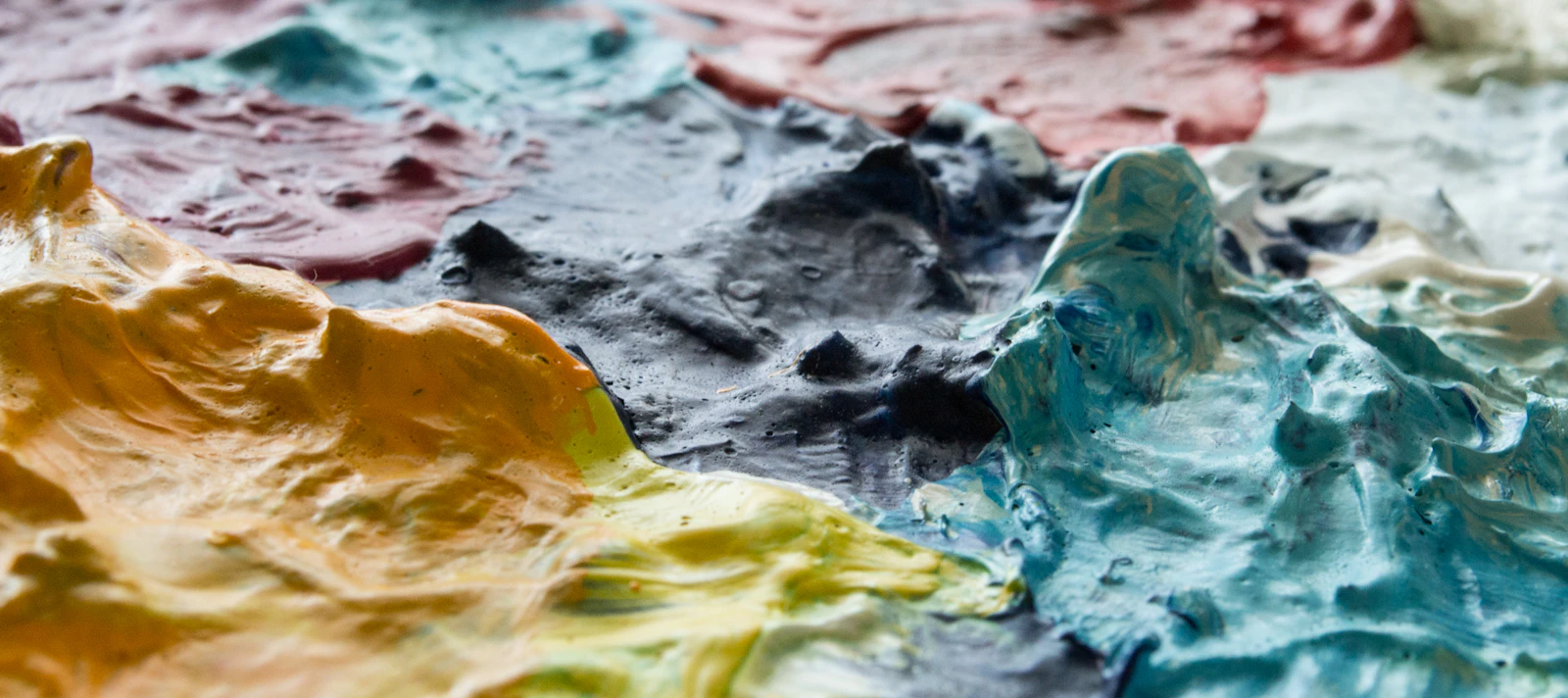 A close-up of a multicoloured artist paint palette with mixed colours