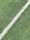 A close-up view of artificial grass with a single white line running diagonally through it, often seen on a sports field.
