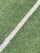 A close-up view of artificial grass with a single white line running diagonally through it, often seen on a sports field.