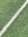 A close-up view of artificial grass with a single white line running diagonally through it, often seen on a sports field.