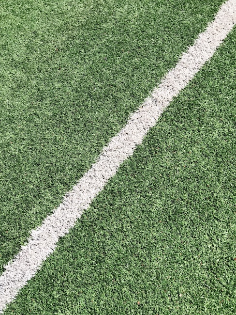 A close-up view of artificial grass with a single white line running diagonally through it, often seen on a sports field.