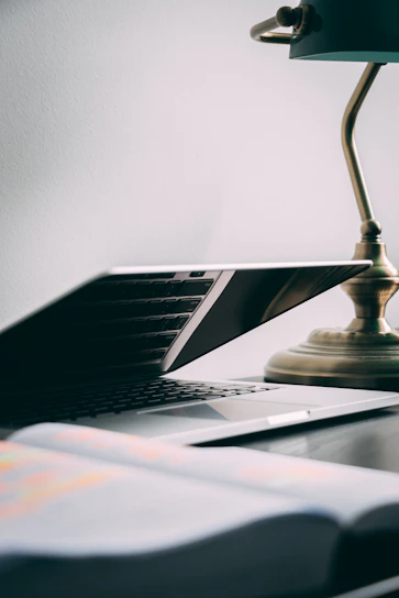 A close-up of a sleek refurbished laptop open on a wooden desk with soft natural light.