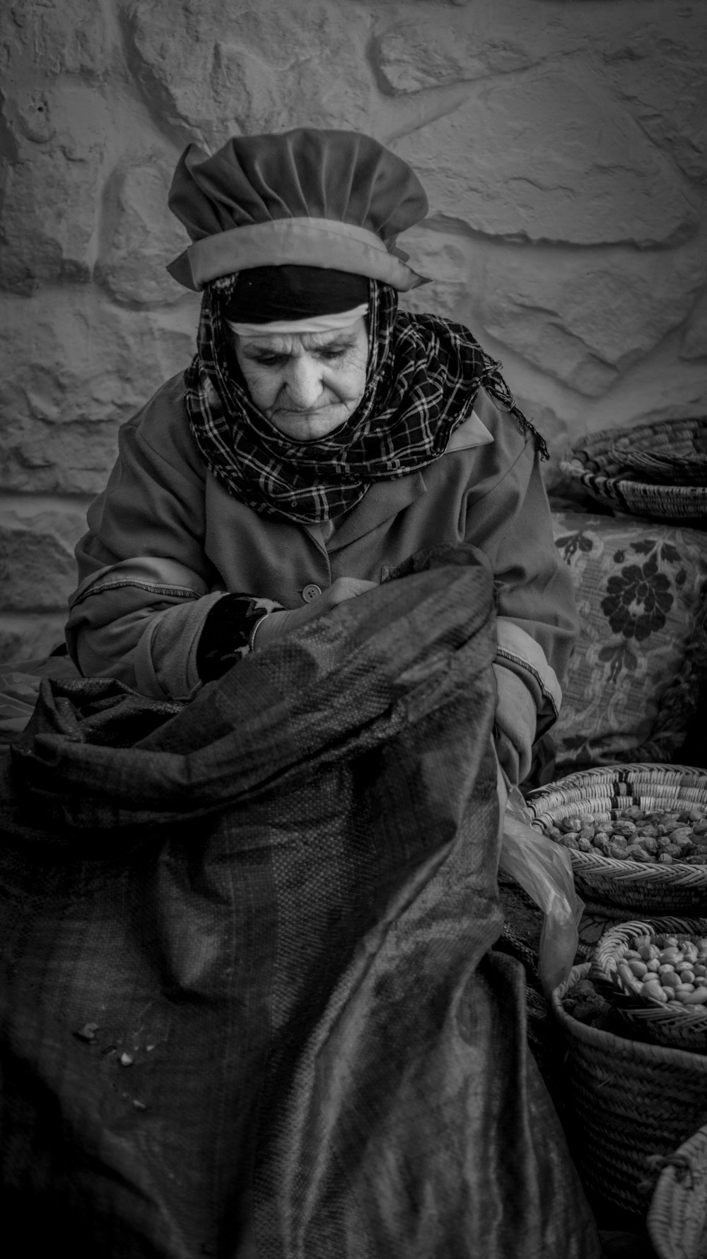 grayscale photo of woman sitting near baskets